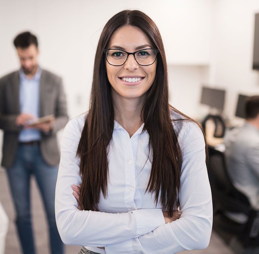 A notary public smiling in an office environment, standing confidently with her arms crossed while ready to assist with legal document notarization.