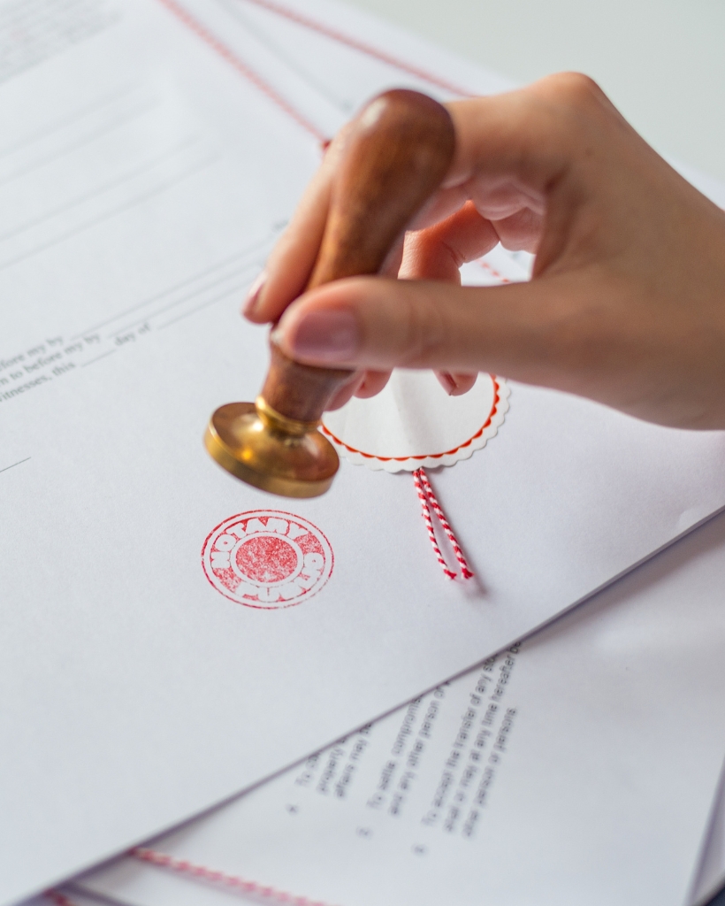 A notary public stamping a legal document with an official notary seal, verifying the authenticity of the document for notarization.