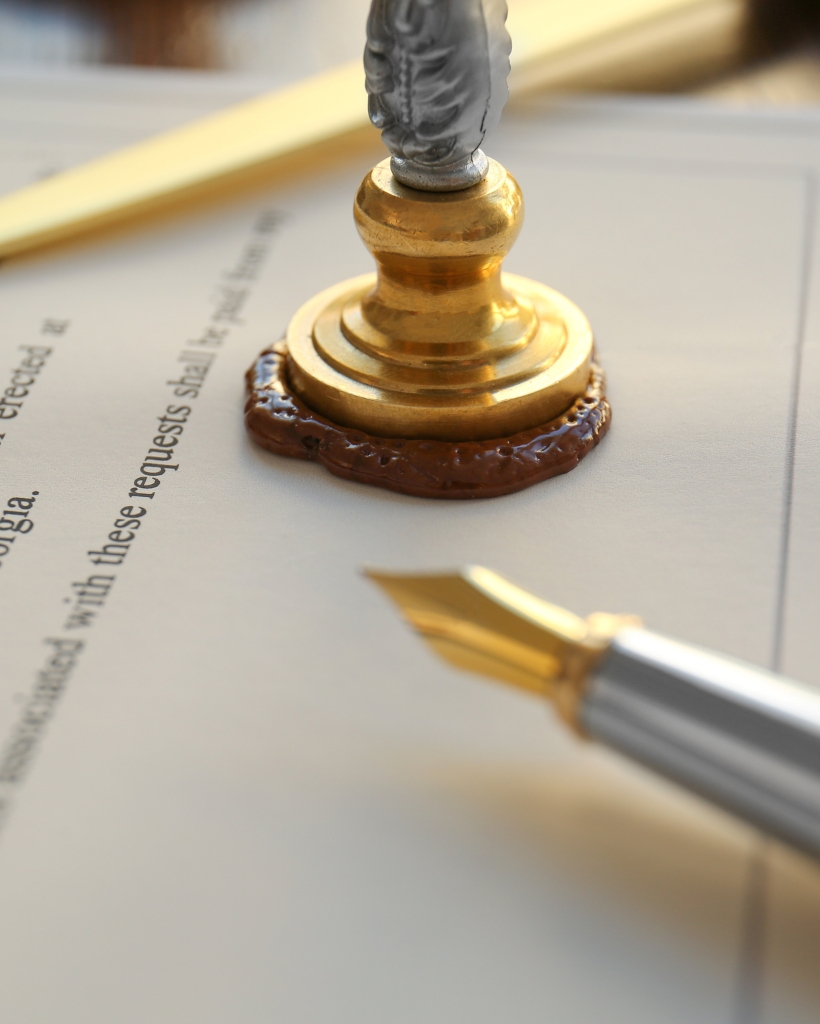 A notary public seal with wax and a fountain pen placed on top of a legal document, ready for notarization and official approval.