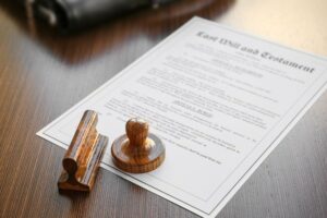 Wooden notary stamp placed on top of a last will and testament document on a wooden desk, representing legal document notarization services.
