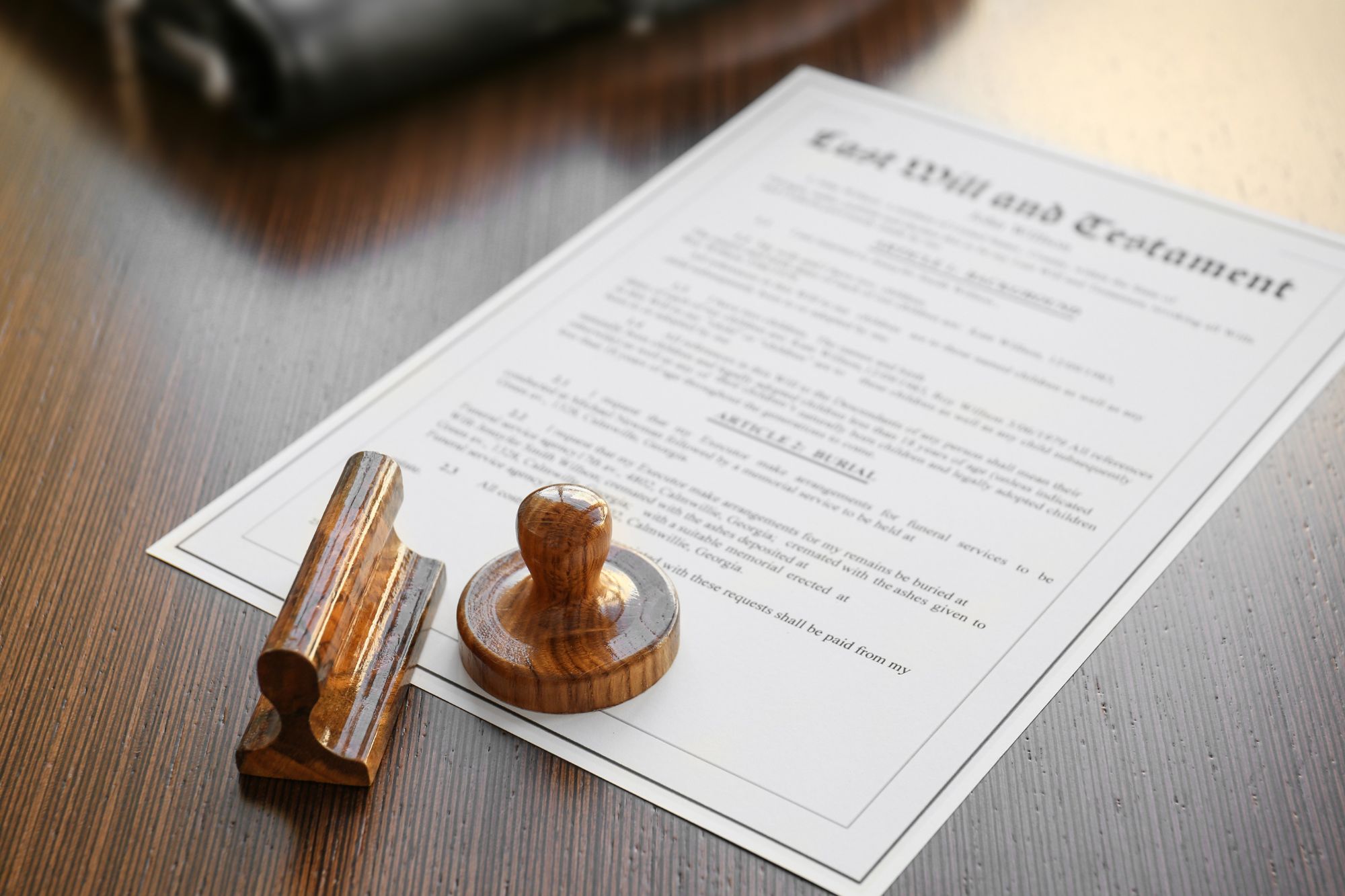 Wooden notary stamp placed on top of a last will and testament document on a wooden desk, representing legal document notarization services.