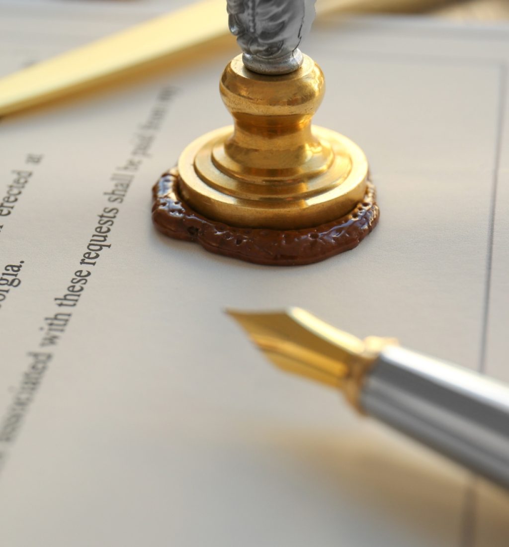 A notary public seal with wax and a fountain pen placed on top of a legal document, ready for notarization and official approval.