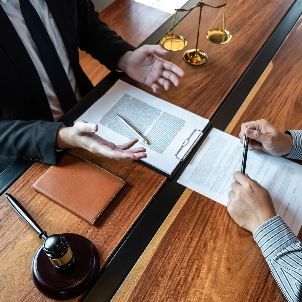 male-lawyer-discussing-negotiation-legal-case-with-client-meeting-with-document-contract-in-office.jpg A client and notary public reviewing and discussing contract terms to ensure all legal requirements are met before notarization.